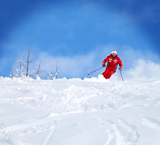 Skilehrer im Schwung vor blauem Himmel